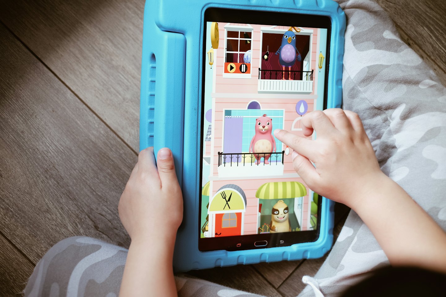 Dziecko grające w edukacyjną grę o zwierzętach na tablecie.